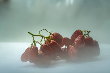 Covered in fine mist, each grape glows with a juicy vibrance that reflects freshness and life. The neutral background emphasizes their rich color and clean, healthy appeal.