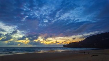 Kumsalda gün batımı renkli bulutlarla