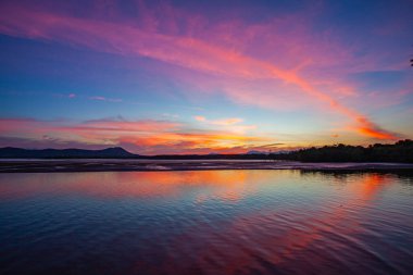 Altın güneş ışığı durgun sular boyunca uzanır. Uzak dağlara doğru hafifçe parlıyordu. Sakin atmosfer ve renkli yansımalar huzuru çağrıştırıyor. Gün batımında gölü mükemmel bir sığınak yapıyor.
