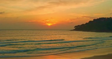 Gün batımının yansımalarının hava görüntüsü ıslak kumda dans ediyor, gökyüzünün rengarenk parıltısını yansıtıyor. Dalgaların hafif kükremesi fısıldayan rüzgarla uyumlu hale gelir. Güzel Karon plajı gün batımında.