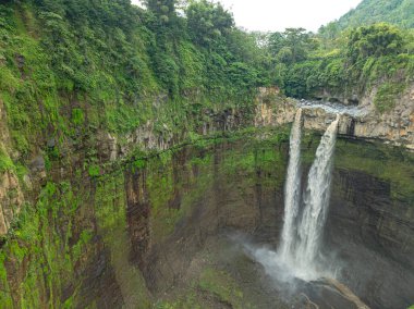 Havadan bakıldığında, Coban Sriti Şelalesi, vadiden aşağı akan ikiz şelale deresi. Su, göz alabildiğince sarmal dağ sırtlarına aktı. yeşil orman  
