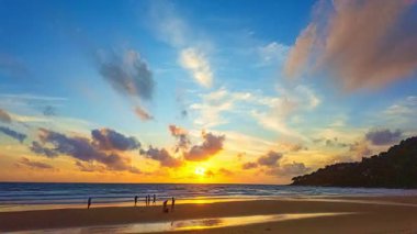 Sahilde gün batımında siluetlerle