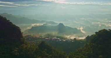 Parlak güneş ışığı altında puslu dağlar