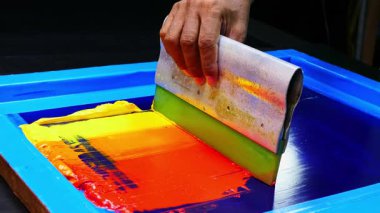 Renkli boyalar üzerinde cam sileceği kullanarak.