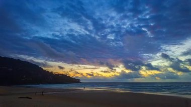 Kumsalda gün batımı renkli bulutlarla