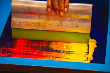 Eller ekran çerçevesine yumuşak sarıdan yoğun kırmızıya renkleri harmanlayan ılık tonlu mürekkepler yayar. Canlı gradyan baskılarda kullanılan dokuyu, hareketi ve sanatçılığı yakalar