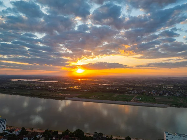 Hava hipersüratli dramatik bulutlar ve solan güneş ışığı kırsal nehir manzarası üzerinde sakin ama güçlü bir atmosfer yaratır. Mekong nehri boyunca uzanan tarlaların yukarısında Altın Saat Hızı
