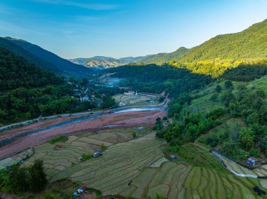 Yeşil pirinç terasları, verimli tarım arazileri ve yemyeşil tepeler ve doğal su yolları arasında yuva yapmış küçük bir köyün yer aldığı pitoresk bir kırsal alan. Dağ Hareketi 'ndeki Şafak Ufku