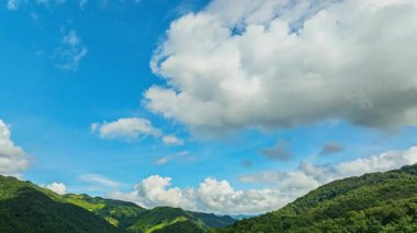 Yeşil dağların manzarası ve gün ışığında yıkanan sakin bir vadi bozulmamış doğayı, temiz havayı ve kırsal kesimdeki sakin yaz koşullarını vurguluyor..