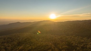 Katmanlı dağ sıralarının üzerinde nefes kesen bir gün batımı. Sıcak altın ışık, derin mavi gökyüzünde kayboluyor. Seyahat ve doğa temaları için ideal, dingin ve geniş bir doğal manzara yaratıyor..