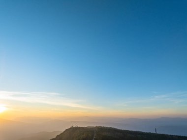 Ilık bir sabah parıltısıyla vahşi doğayı aydınlatan, uzak sırtların üzerinden hafif ışınlar yükselir. Bu zaman atlaması, ufukta yayılan bir dağ gündoğumunun huzurlu güzelliğini gözler önüne seriyor..