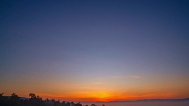 Katmanlı dağ sıralarının üzerinde nefes kesen bir gün batımı. Sıcak altın ışık, derin mavi gökyüzünde kayboluyor. Seyahat ve doğa temaları için ideal, dingin ve geniş bir doğal manzara yaratıyor..
