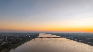 Kong nehri köprüsünde muhteşem bir gün batımı. Dramatik bulutlar, altın saat ışığı ve suya yansıyan yansımalar. Bu resim kentsel altyapı, ulaşım, şehir manzarası ve alacakaranlığı gösteriyor