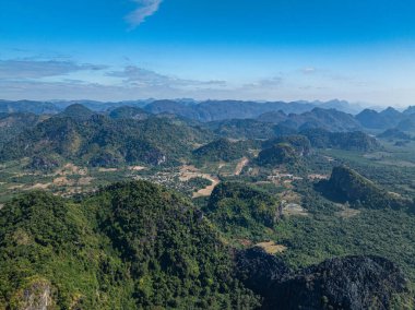Uçsuz bucaksız bir ormanın üzerinde sabah güneşinin dingin bir görüntüsü ufukta belli belirsiz görünen dağların zirveleri barışçıl ve ruhani bir manzara oluşturuyor. Mavi gökyüzünde bulut