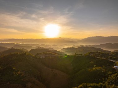 Tayland 'ın Nan Eyaleti' ndeki yüksek bir tepede, kıvrımlı bir dağ yolunda parlayan altın günbatımı ışığı çarpıcı bir kıvrım, zirveler ve sıcak akşam atmosferi manzarası yaratıyor..