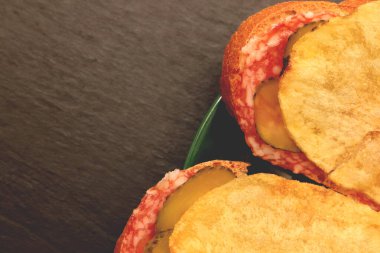 Ekmek dilimli sandviçler peynir, salatalık ve yeşil tabakta cips. Arka plan dolduruluyor.