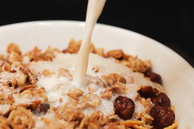 Çikolata toplu mısır gevreği dilimlenmiş muz ve süt deresi. Dolduruluyor. Makro yakın plan.