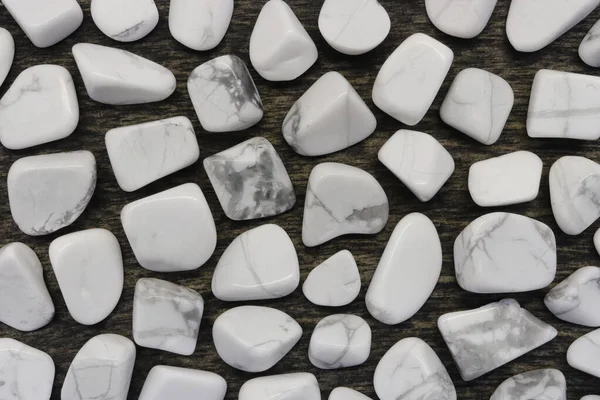 White turquoise rare jewel on black stone texture. Scarce mineral pebbles background.
