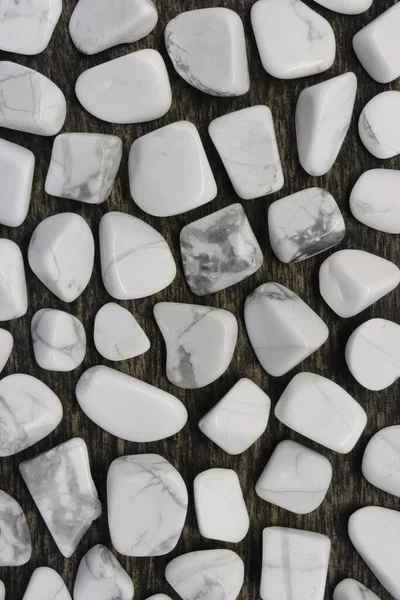 White turquoise rare jewel on black stone texture. Scarce mineral pebbles background.