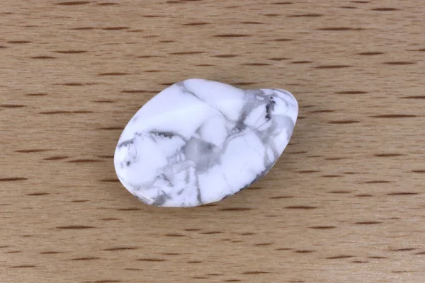 White turquoise jewel stone texture on light wood background. Macro closeup