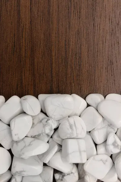 White turquoise jewel heap on light varnished wood half background. Pile mineral pebbles texture. Place for text.