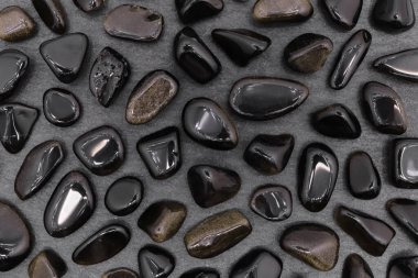 Siyah taş dokusunda altın obsidiyan nadir mücevher. Mineral çakıl taşı arkaplanı.