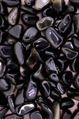 Açık ahşap desenli altın obsidiyan mücevher yığını. Yığın mineral çakıl taşı arkaplanı.