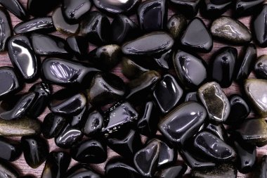 Açık ahşap desenli altın obsidiyan mücevher yığını. Yığın mineral çakıl taşı arkaplanı.