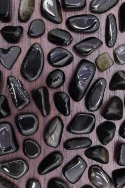 Kahverengi ahşap arka planda altın obsidiyan mücevher dokusu. İnce mineral çakıl taşları yaratıcı.