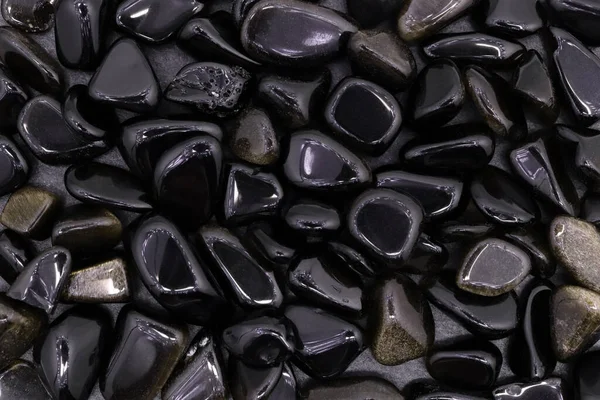 Açık ahşap desenli altın obsidiyan mücevher yığını. Yığın mineral çakıl taşı arkaplanı.