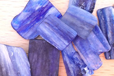Hafif verniklenmiş ahşap arka planda kyanit yığını mücevher dokusu. Nadir bulunan çakıl taşları doğa arkaplanı.