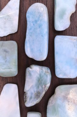 Larimar nadide mücevheri yarım kahverengi ahşap dokusunda. Yığın mineral çakıl taşı arka planı. Metin için yer.