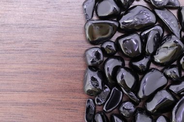 Yarı kahverengi ahşap dokusunda siyah turmalin nadir mücevher. Yığın mineral çakıl taşı arka planı. Metin için yer.