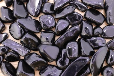 Tahta testerenin arka planındaki siyah turmalin mücevher dokusu. Yığın mineral çakıl taşları doğa arka planı.