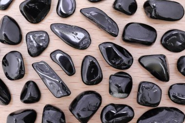 Tahta testerenin arka planında nadir bulunan siyah turmalin mücevher dokusu. Nadir bulunan çakıl taşları doğa arkaplanı.