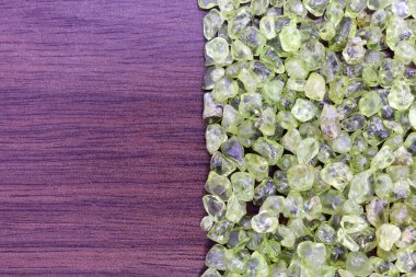 Yarım kahverengi ahşap desenli Olivine hurda mücevheri. Yığın mineral çakıl taşı arka planı. Metin için yer.