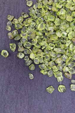 Olivin mücevheri siyah taş arka planda üst üste yığılır.
