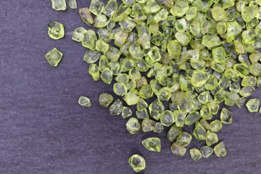 Olivin mücevheri siyah taş arka planda üst üste yığılır.