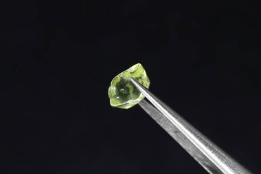 Siyah yüzey arka planında cımbızla yapılmış Olivine mücevher dokusu. Makro yakın çekim.