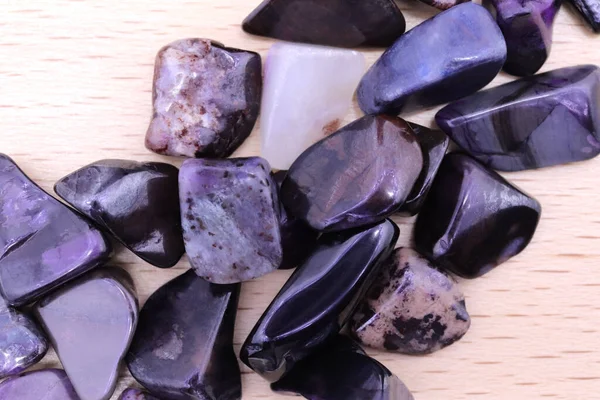 Sugilite mücevher taşları parlak ahşap dokuya yığılır.