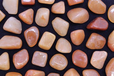 Kırmızı Aventurine, siyah arka planda nadir bulunan mücevher dokusu. Mineral çakıl taşları arkaplan.