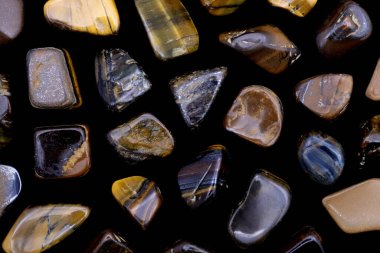 Siyah arka planda Tiger 's Eye nadir bulunan mücevher dokusu. Mineral çakıl taşı arkaplanı.