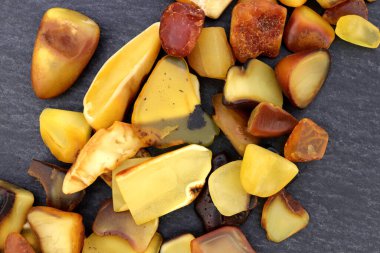 Kehribar mücevher taşları siyah taş arka planda üst üste yığılır.