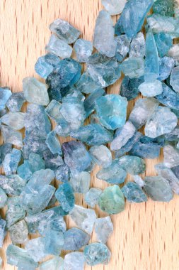Apatite jewel stones heap up texture on light varnished wood background clipart