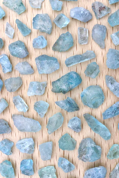 Apatite rare jewel stones filled texture on light varnished wood background.