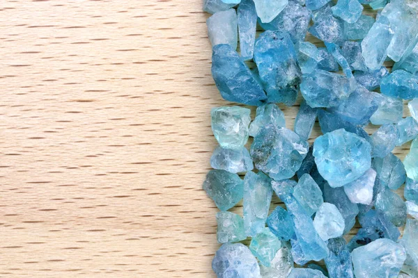 Apatite heap jewel stones texture on half light varnished wood background. Place for text.