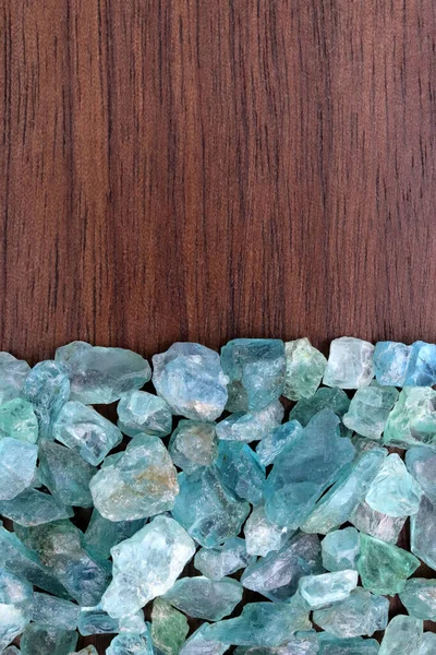 Apatite heap jewel stones texture on half brown varnished wood background. Place for text.