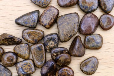 Bronzit mücevher yığınını parlak ahşap zemin üzerine yığar.