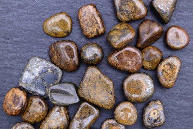 Bronzit, siyah taş arka planda mücevher parçalarını üst üste yığar.