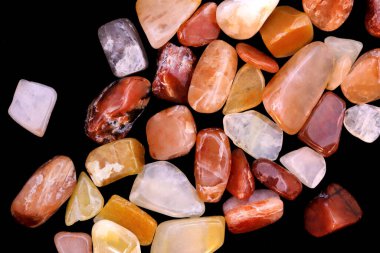 Kırmızı ipek taşlı yeşim taşları siyah arkaplandaki dokuları üst üste yığıyor.